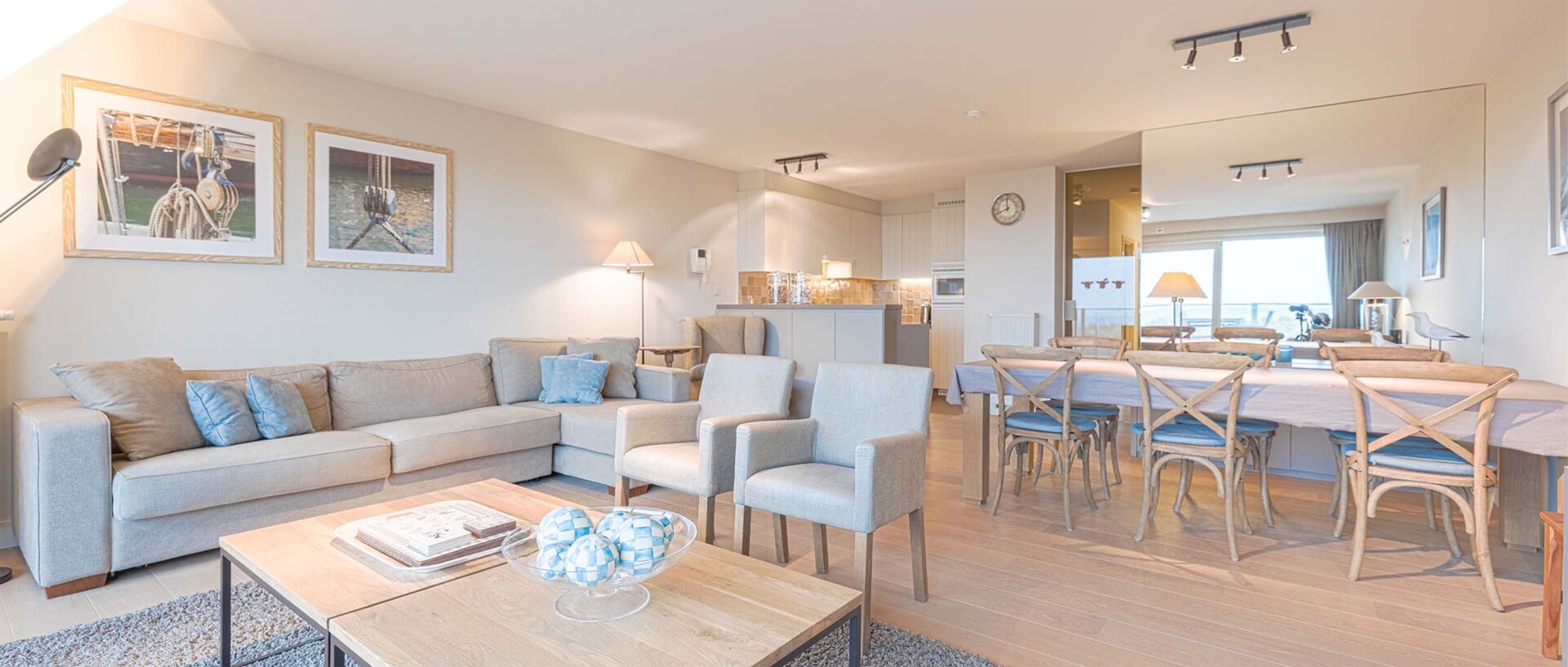 Moderne, lichtrijke woonkamer met open keuken en houten accenten in een appartement aan de kust