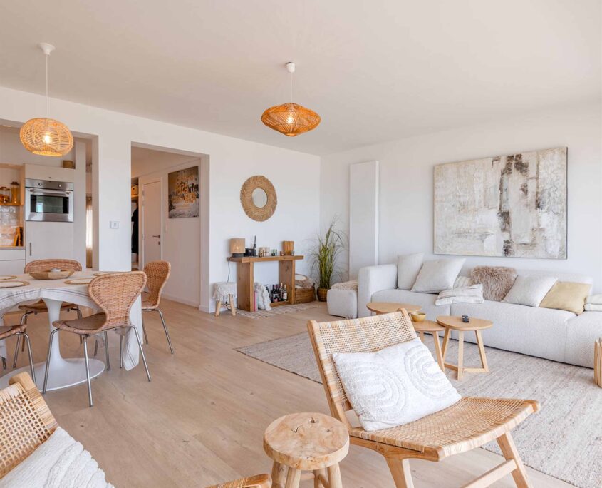Moderne, lichtrijke woonkamer met open keuken en houten accenten in een appartement aan de kust